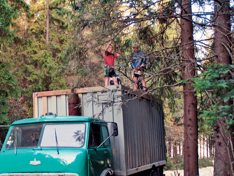 Немудрёная педагогическая наука: пацаны сами готовят себе трассу, обрезая пилой и сучкорезом сучья с крыши грузовика. 